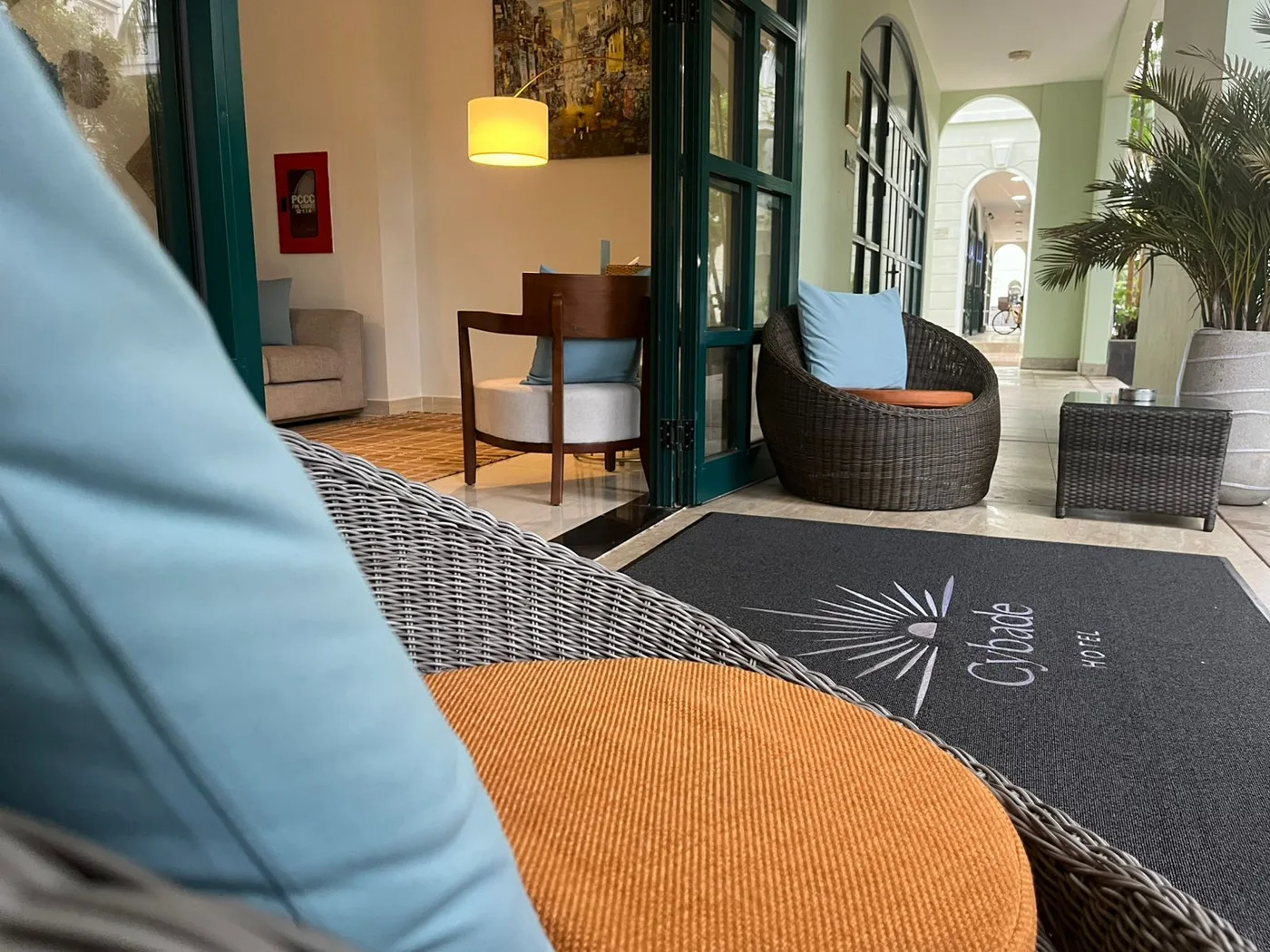 Fauteuils en rotin de l'entrée, devant le tapis de bienvenue Cybade
